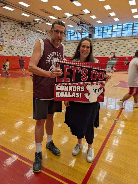 Connors parent cheering with a Let's Go Koalas sign