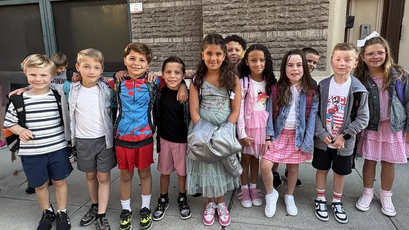 A row of Connors kids with backpacks lined up arm in arm outside school