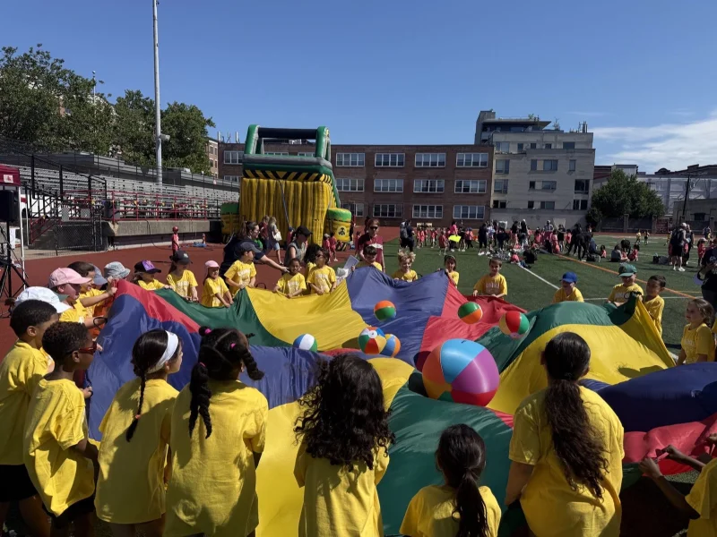 Connors students in yellow shirts playing a parachute game with beach balls at Field Day