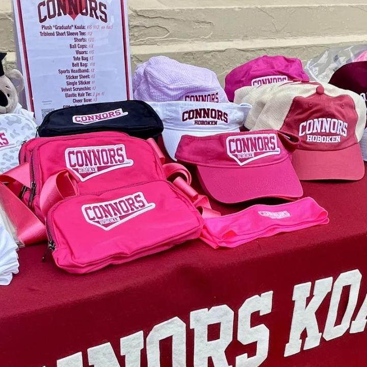 Pink Connors belt bags, visors, and ball caps on the Connors Koalas table cover