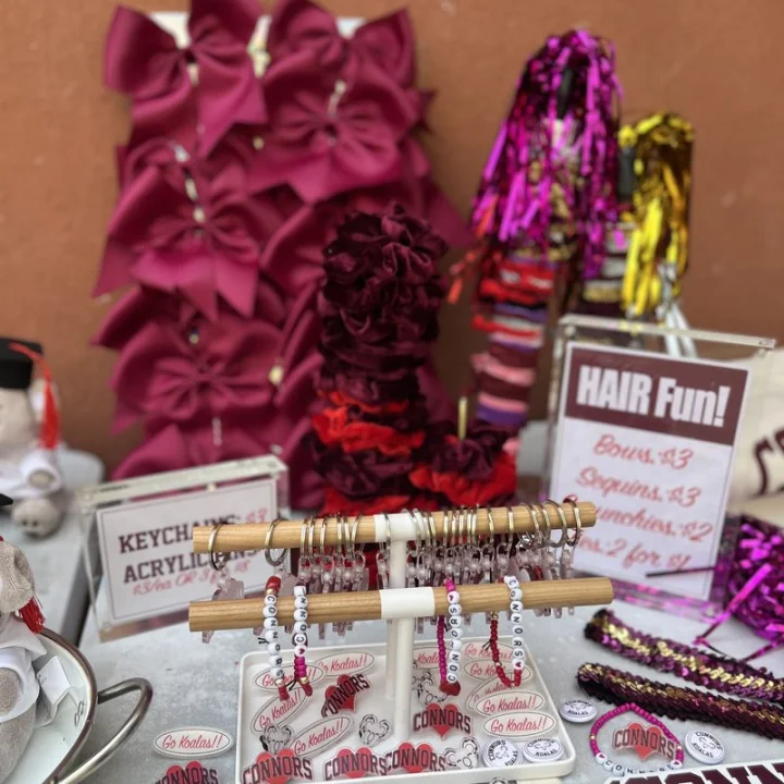 Maroon hair bows, velvet scrunchies, and pink poms on a swag table
