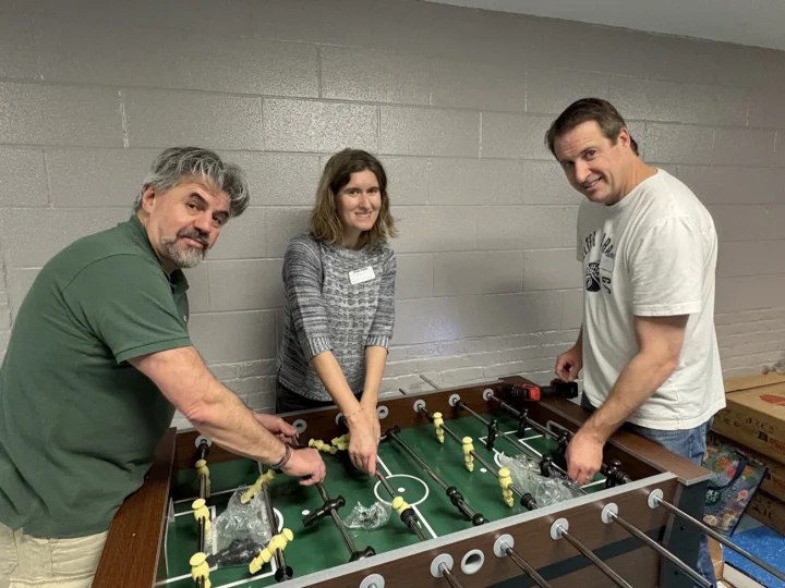 Three Connors parents assembling a foosball table with a drill